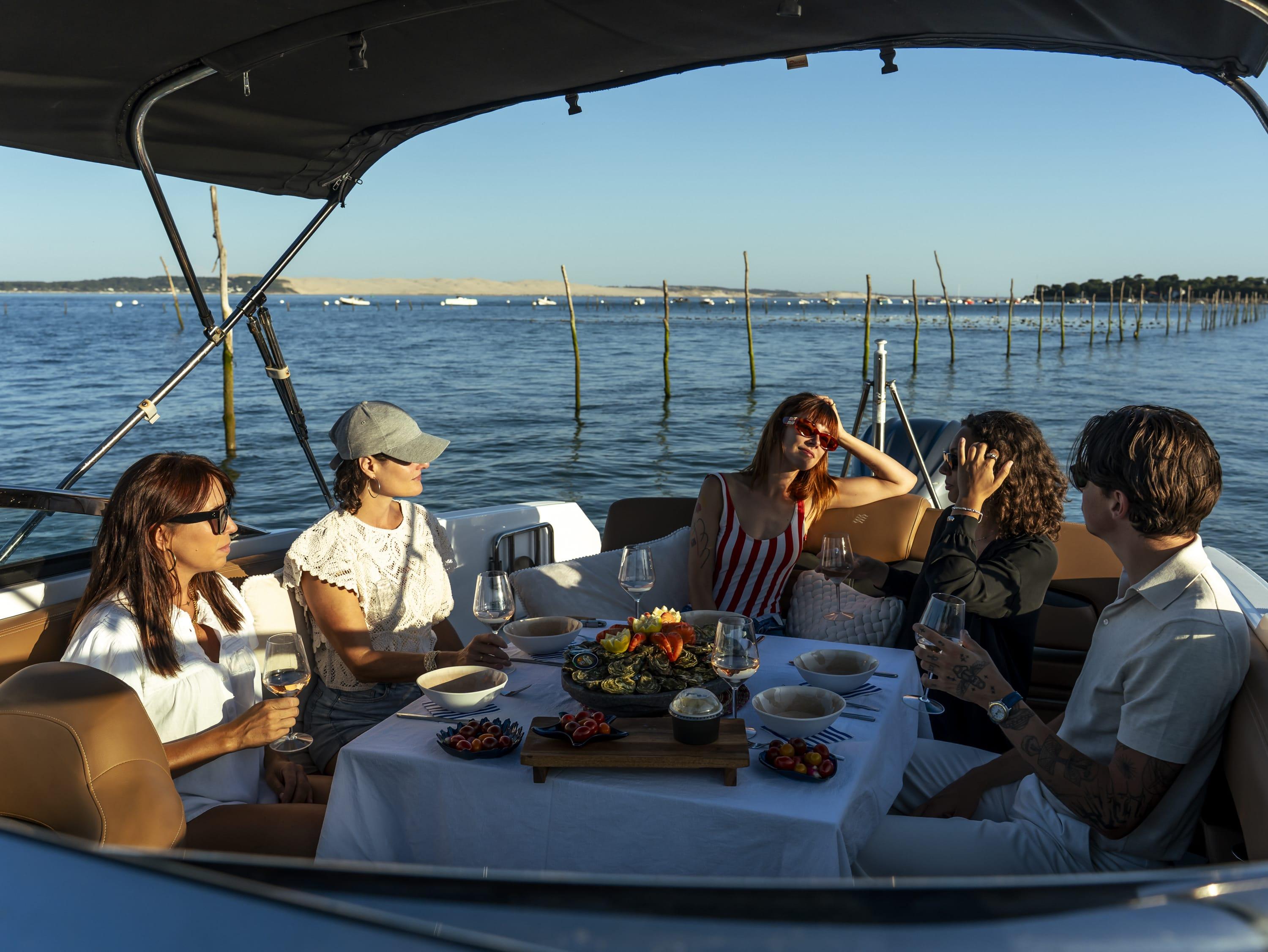 Groupe d'amis profitant d'un apéritif sur un bateau face aux parcs à huîtres du Bassin d'Arcachon.